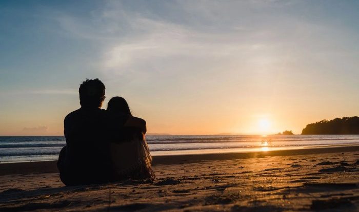 Two lovers and a beachcomber by the real sea